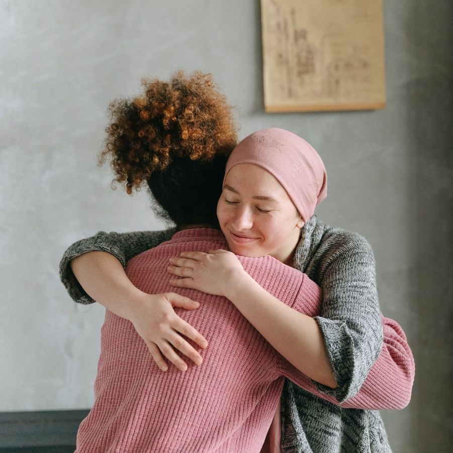 Cancer patient hugging woman in pink sweater